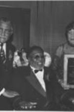 Joseph and Evelyn Lowery pose for a photo with Curtis Mayfield at the 15th Annual SCLC/W.O.M.E.N. Drum Major for Justice Awards dinner. Mayfield was the recipient of the Drum Major for Justice Award for Musical Heritage. Written on verso: Dr. &amp; Mrs. Lowery w/ Curtis Mayfield.