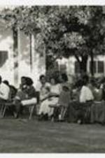 View of men and women sitting on chairs on the lawn in front of Clement Hall.