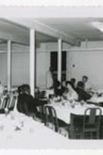 A group of men and women sit at buffet tables.