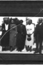 View of an unidentified group of men and women standing outside.