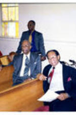 Dr. L. Henry Whelchel sits in a pew with other unidentified men.