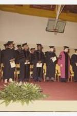 Indoor view of men and women wearing caps and gowns. Written on verso: "Morris Brown College; Founders Day Mid 70's".