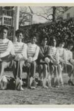 A group portrait of the Majorettes on a bench on a football field.