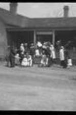 Women gather with children and babies outside of the neighborhood house.
