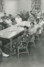 A group of unidentified people sit in a room at a gathering.