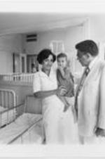 Southern Christian Leadership Conference (SCLC) President Joseph E. Lowery speaks with a nurse holding a toddler as another young child sitting on a bed looks on. Lowery was with members of a SCLC delegation on a peace mission in Lebanon.