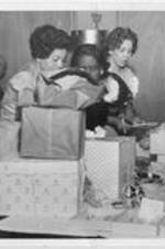Evelyn G. Lowery (at back of photo) is shown with two other women looking at a table of wrapped gifts.