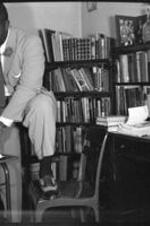 C. Eric Lincoln stands and reads a book in his office.