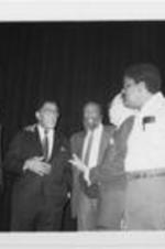 Southern Christian Leadership Conference officials, including (L to R) Sevell Brown, III, E. Randel. T. Osburn, SCLC President Joseph E. Lowery, Dick Gregory, and others meet during an event for SCLC's campaign against youth drug and alcohol abuse. Written on verso: SCLC officials discuss format of program about to begin.