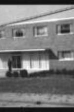 Exterior view of an unidentified building with a man standing at the entrance, possibly student apartments.
