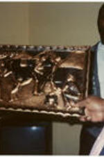 A man holds a plaque as C. Eric Lincoln and others look on.