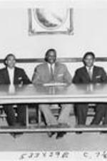 A group of men sit behind a desk. Written on verso: Middlers- 1959. Left to Right: Raymond J. Gibson, John D.V. Hamilton, Jr., Carrol M. Felton, Isaac Mullins, Therman Taylor.