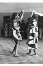 A couple dance together on a dance floor wearing matching patterned attire.