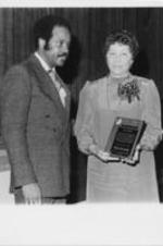 Evelyn G. Lowery is shown with John Nettles receiving an award during a Calhoun County, Alabama SCLC Chapter banquet. Written on verso: Chapter News -- Mrs. Evelyn G . Lowery, national convener of SCLC/WOMEN, displays the "Distinguished Service Award" presented to her by the Calhoun County chapter of SCLC in Alabama during its annual awards dinner. Mrs. Lowery was saluted for "her unequaled dedication to the struggle" and her leadership in organizing the Calhoun County chapter of SCLC/WOMEN.