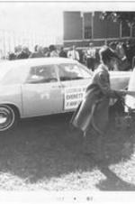 A woman reaches towards her child near a campaign car at a political rally for Everett Millican at Morris Brown College.