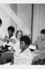 Vice President Dan Quayle sits with others, including Evelyn G. Lowery (seated next to Quayle), and studies a document being handed out to attendees. Quayle was attending a tour of the SCLC/WOMEN Learning Center in Atlanta, Georgia.