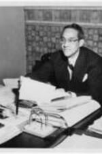 Raymond Alexander reads papers at his desk.