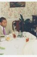 Wynton Marsalis and Thomas W. Cole, Jr. sit at a dining table in a room with floral wallpaper.