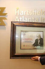 An unidentified person out of frame holds a framed image congratulating Joseph E. Lowery on receiving the 2009 Presidential Medal of Freedom during an event honoring Lowery at the Hartsfield-Jackson Atlanta International Airport.
