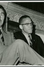 A. C. Powell sits next to Malcom X.Written on verso: Photographer: Robert Haggins, Malcom X's Personal Photographer.