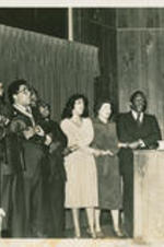 Joseph E. Lowery is shown holding hands with others and singing at a Martin Luther King, Jr. birthday celebration held at New Pilgrim Baptist Church in Birmingham, Alabama. Written on verso: MLK birthday - '80, Birmingham - Nelson Smith's church