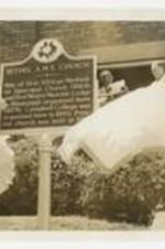 A man unveils a historic site sign at Bethel AME Church.