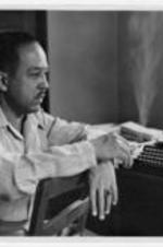 Langston Hughes sits by a typewriter.