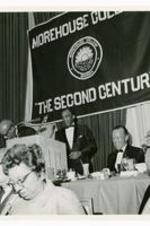 View of man standing at a podium, banner in background "Morehouse College, 'The Second Century' ."