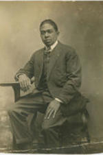 Portrait of an unidentified man sitting on a stool.