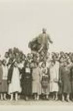A group portrait of unidentified people stand in front of a statue of Booker T. Washington.