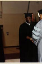 An unidentified graduate shakes hands with President Grant Shockley.
