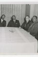 Written on verso: Left to Right Administration Meeting, 1. Dr. J. deKoven Killingsworth - Department Chairman - music, 2. Dr. Wiley S. Bolden - Dean of faculty/Instruction, 3., 4. Dr. Johnathan Jackson - College Minister/Ass. Professor, 5. Pres. Brawly, 6., 7., 8. Dr. Herbert F. Rogers? Chair of Religion/Philosophy, 9. Mr. Hugh G. Black, English Instructor.