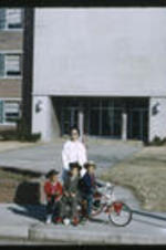 Anna Henderson and three children in front of an unidentified school building.