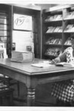 A woman studies at a table in the periodical area of the Gilbert Haven Memorial Library.