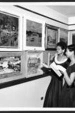 Two unidentified women admire artwork at the 16th annual art exhibition.