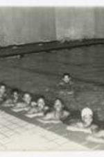 Indoor view of men and women in a swimming pool. Written on verso: "Mr. Edward Weaver MB College; P.E. Instructor Physical Ed. Dept."