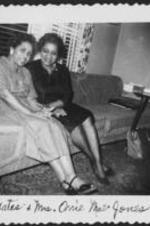 Mrs. Yates &amp; Mrs. Orrie Mae Jones sit on a sofa in a living room. Written on recto: Mrs. Yates &amp; Mrs. Orrie Mae Jones.