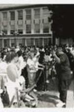 Two men perform for a crowd on the steps of a building at a homecoming concert.
