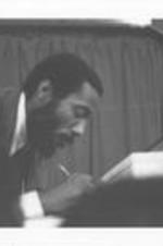 Dick Gregory bends down to write something at an event.