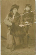 An unidentified woman sits in a chair while her daughter sits on the arm of the chair.