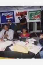 R&amp;B Group 112, Lil Zane, and Alumni Janaye Ingram sit in a pop-up tent with microphones, a banner "Pepsi, Hot 97.5, Mountain Dew" hangs in the background.