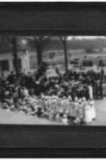 View of an unidentified group of people gathering ouside on a lawn.