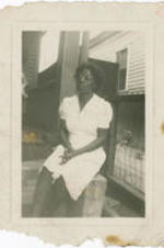 Portrait of an unidentified woman sitting on the steps of a porch.
