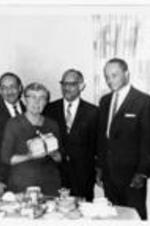 Dr. Hyla S. Watters stands with Harry V. Richardson and Directors while holding a wrapped gift in her hands. Written on verso: 2/22/68 Dr. Hyla S. Watters visits L.T.C. - seen with HVR &amp; Directors.
