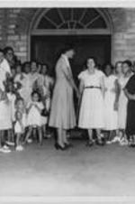 Mrs. C. R. Yates of Carrie Steel Pitts Home walks out of a building surrounded by women and children.