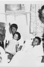 Reverend Jesse Jackson (at right) poses for a photo with a child and two other individuals at Provident Hospital in Chicago, Illinois. Written on verso: "Soul Santa" Visits Provident Hospital -- Little Barbara Scott is enjoying a "Beautiful Black Christmas" even if she is a hospital patient in Provident Hospital. Barbara was visited this week by "Soul Santa" and Rev. Jesse L. Jackson, National Director of SCLC's Operation Breadbasket. "Soul Santa" is visiting black people in other hospitals and institutions including Cook County Jail and other penal institutions. Children can also visit "Soul Santa" at Black Christmas Headquarters in the 51st and State Shopping Center. Hours are on weekdays 6pm to 9pm, and after 4pm on Saturday and Sunday.