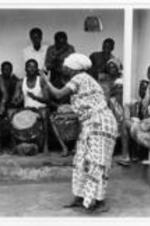 An unidentified woman performs a dance with drums.