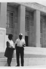 An unidentified man and woman talk outside of a county court house.