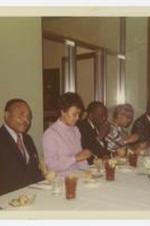 Edward A. Jones and others sit at a luncheon table. Written on verso: E.A. Jones, Beulah Gloster, Howard Thurman, O. Watson, M.N. Watson