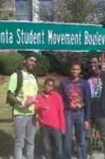 A group of young men stand under the Atlanta Student Movement Boulevard sign during the dedication celebration.